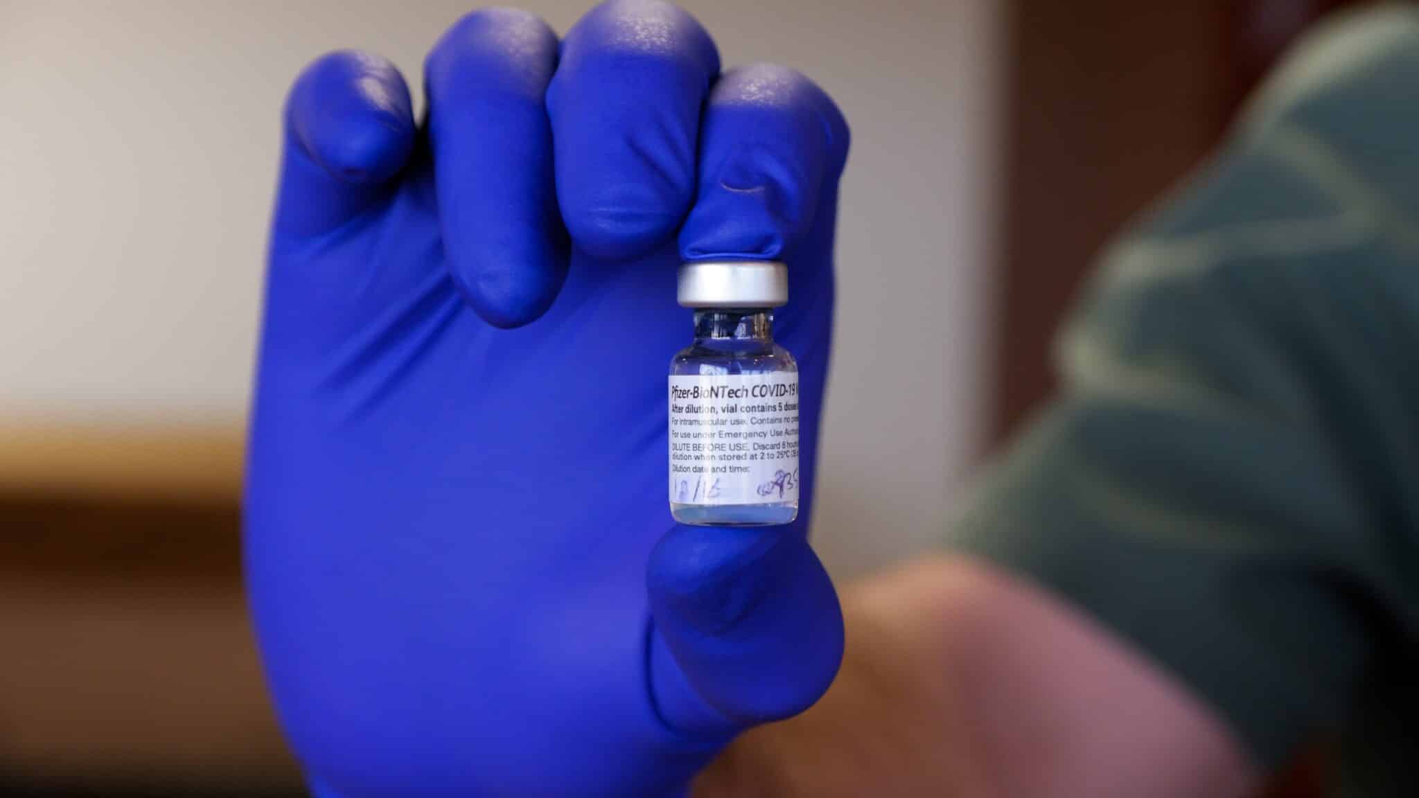 Josiah Jansen, who works in the pharmacy at Presbyterian St. Luke's Medical Center in Denver, holds up a vial of Pfizer's coronavirus vaccine on Wednesday, Dec. 16, 2020.