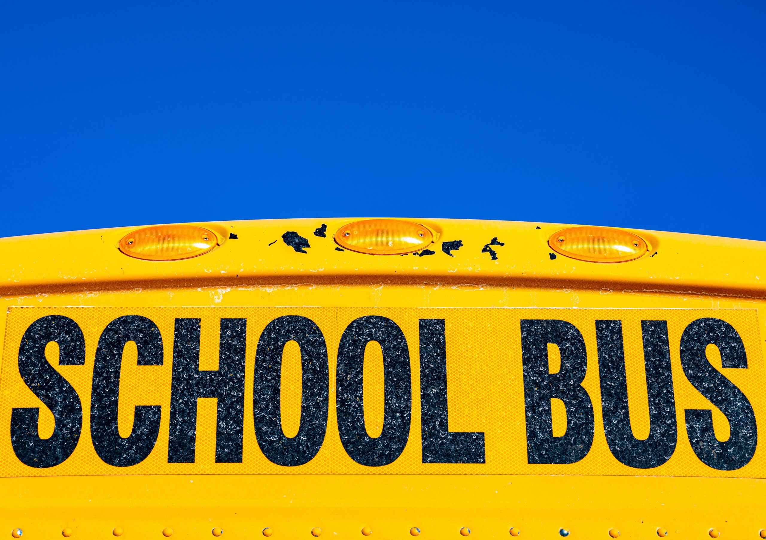 lettering saying school bus on the front of a yellow bus